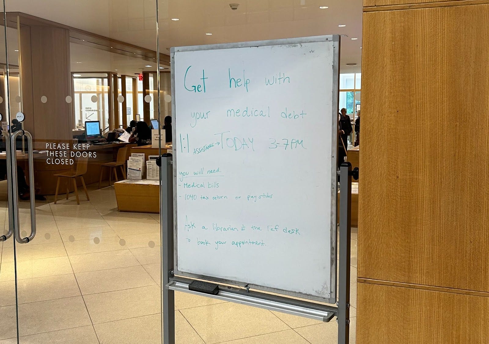 Whiteboard with text on it in front of library doors